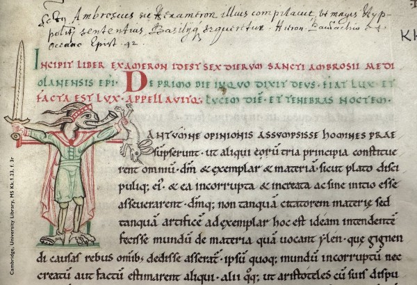 Detail of a leaf in a medieval manuscript: folio 3 recto in Cambridge, University Library, manuscript Kk.1.23. Across the very top sprawls a 3 line annotation added by a modern hand in black ink. Below this, the original contents open with 3 lines of Latin copied in alternating red and green ink; following this are 9 lines of Latin copied in black ink. The first 7 black ink lines are indented to accommodate an enlarged decorative initial ‘T’ rendered in black, red, and green ink. The stylized initial takes the form of a demonic creature clad in human garb: a scarlet cape over a grass green tunic, with a scarlet headband. Although he has the body of a man, one of his feet is a ruminant’s hoof; the other, a bird’s foot. His head is that of a goat with long, faintly spiralling horns. Standing upright, he spreads his arms out at shoulder level, grasping a sword in one hand and a panic-stricken rabbit in the other, while sounding the hunting horn protruding from his grinning mouth.