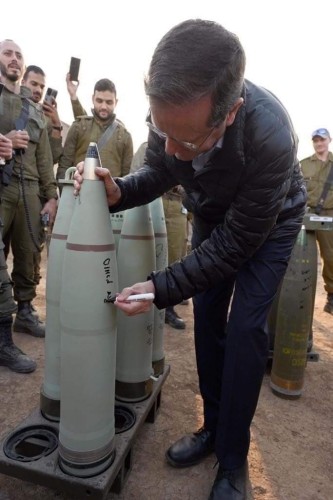 Herzog is autographing a bomb in front of a group of Israeli soldiers 