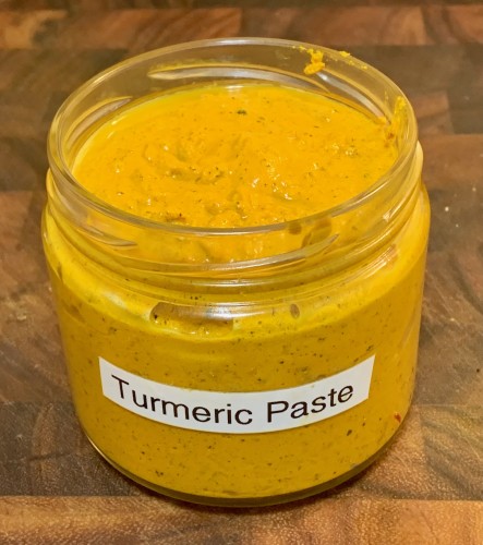 A squat jar with a homemade label that says "Turmeric Paste." The jar is filled with a yellowish-orange paste.