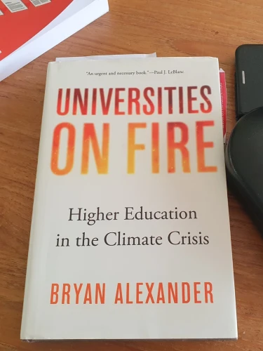 Photograph of a white book cover with red-orange letters. Reads "Universities on fire: Higher education in the climate crisis" Author Bryan Alexander.