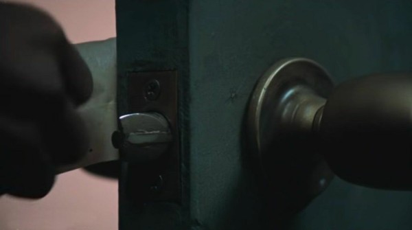 A hand peeling tape away from a door handle, which has been used to keep the door from shutting completely