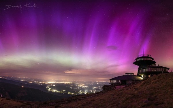 The futuristic buildings on the right are part of a meteorological observatory located on the highest peak of the Karkonosze Mountains. The purple color is primarily due to Sun-triggered, high-energy electrons impacting nitrogen molecules in Earth's atmosphere.